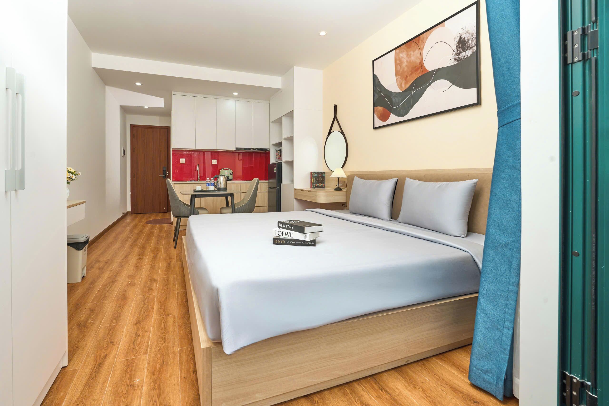 Habitación de hotel con cama, escritorio, silla, kitchenette y baño.