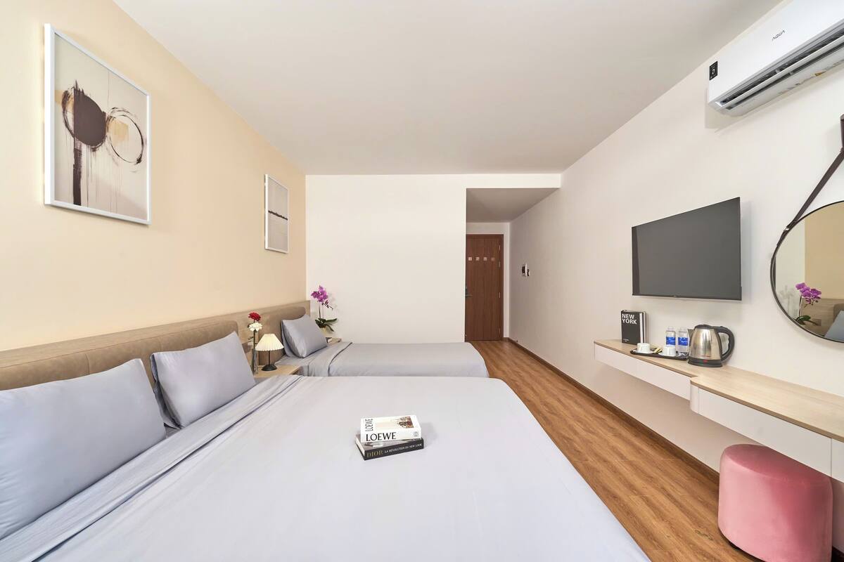 Habitación de hotel con dos camas, un televisor, una cafetera y un espejo en la pared.