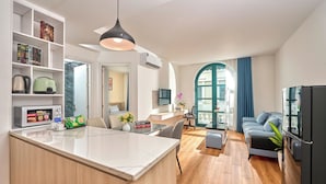 A modern kitchen with a marble countertop, a built-in bookshelf, and a dining area with a glass table. - Lumiere Boutique Phu Quoc Hotel (Phu Quoc)