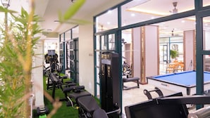 A gym with exercise equipment, a pool table, and a seating area with tables and chairs. - Lumiere Boutique Phu Quoc Hotel (Phu Quoc)