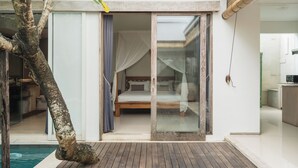Un dormitorio con cama, puerta corrediza de vidrio y vista a una piscina.