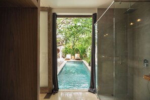 A glass-enclosed shower area adjacent to a pool with a view of outdoor seating and greenery. - Villa Lestari 1 by Alfred in Bali (Kerobokan)