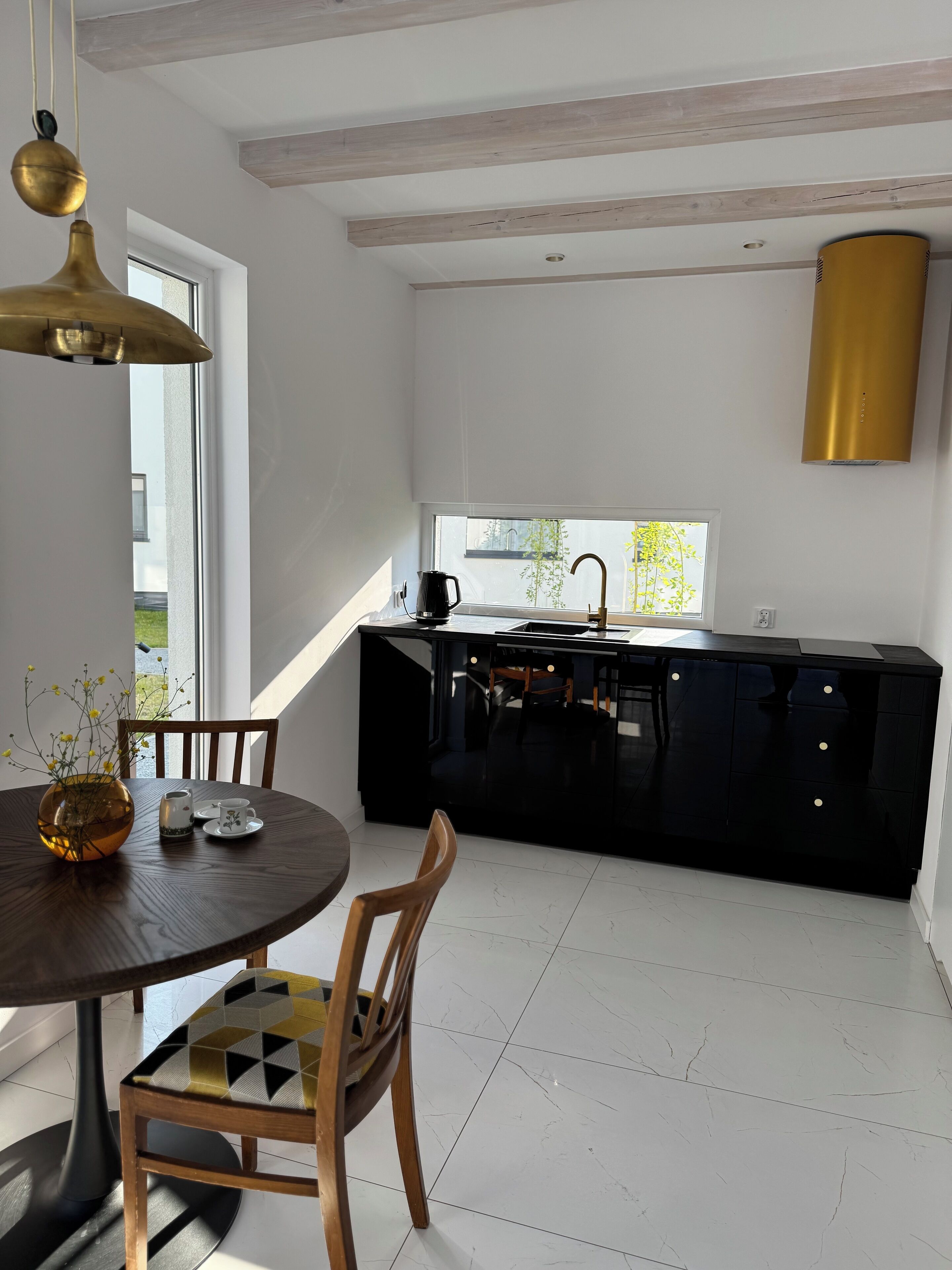 A modern kitchen with a black countertop, a window, and a dining area with a table and chairs.