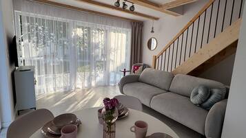 A modern living room with a sofa, dining table, and staircase.