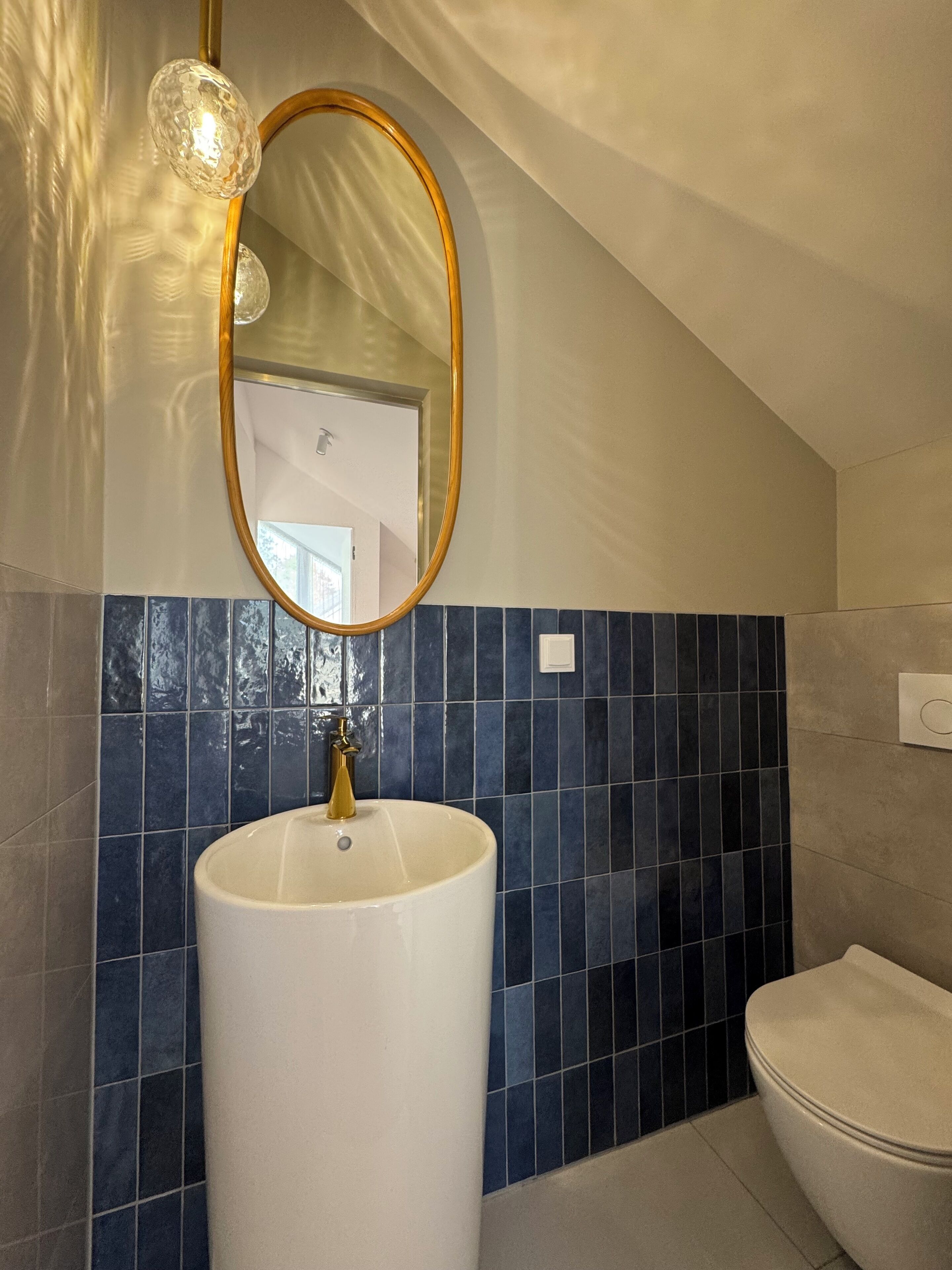 Une salle de bain avec un lavabo blanc, un robinet doré et un mur recouvert de carreaux bleus.