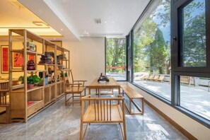 Un intérieur moderne avec un coin repas, des meubles en bois et de grandes fenêtres.