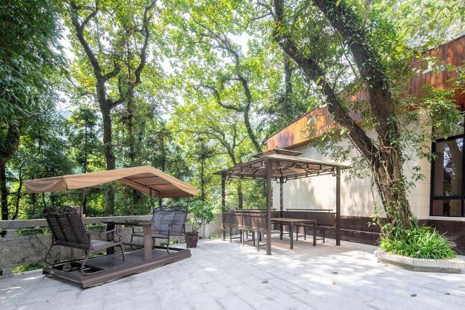 An outdoor patio with a table and chairs, a pergola, and a view of a building.