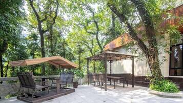An outdoor patio with a table and chairs, a pergola, and a view of a building.