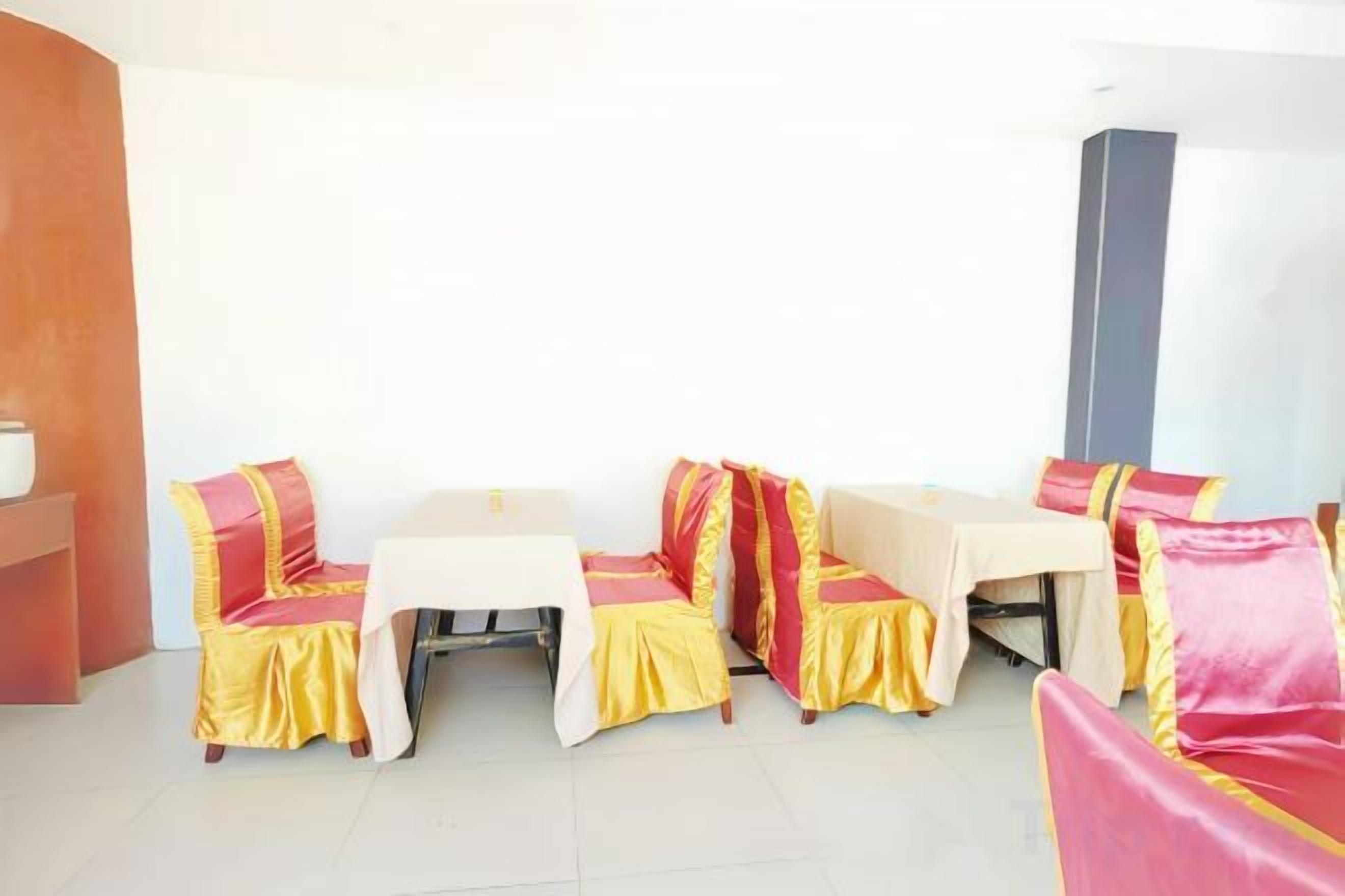 A room with a sofa set and a table, both covered with yellow and red fabric.