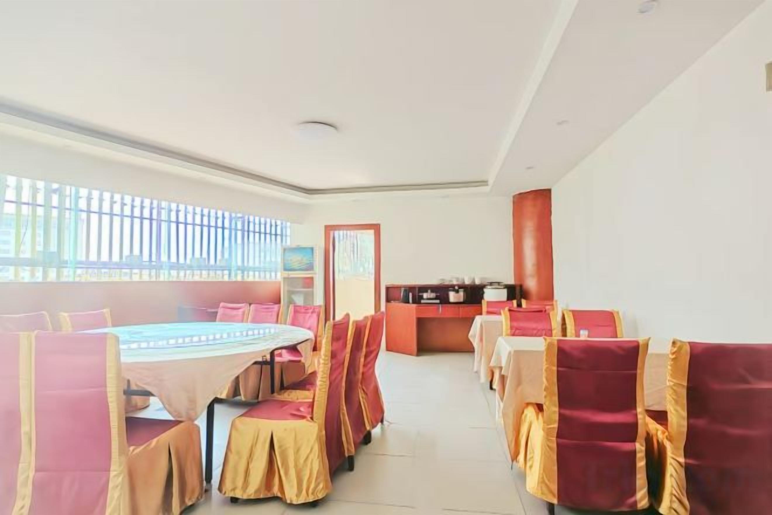 A dining area with a long table and chairs, a counter, and a window with blinds.