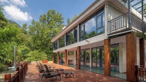 A modern building with large windows and a balcony overlooking a garden. - Babaling Leisure Hostel (Hengyang)