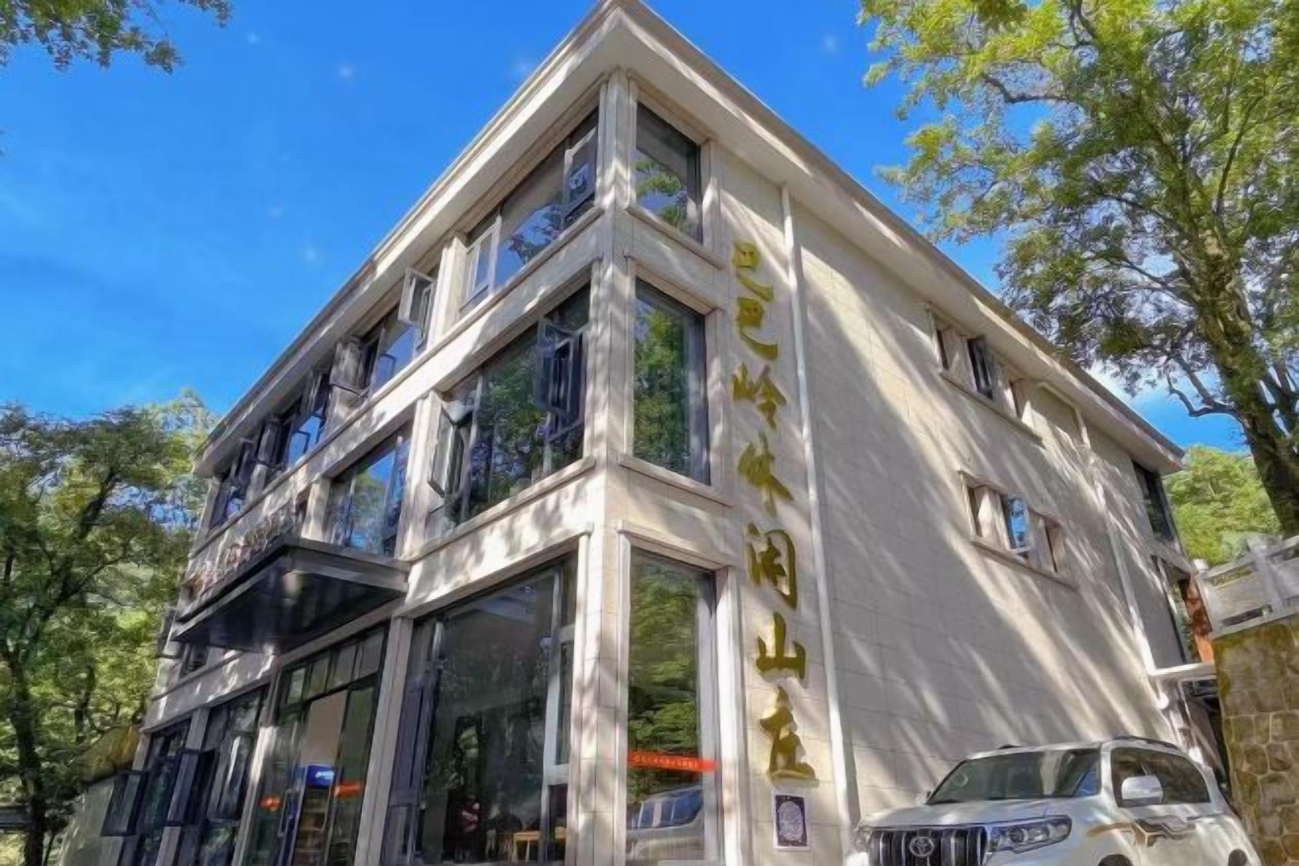 A multi-story building with large windows and a balcony on the second floor.