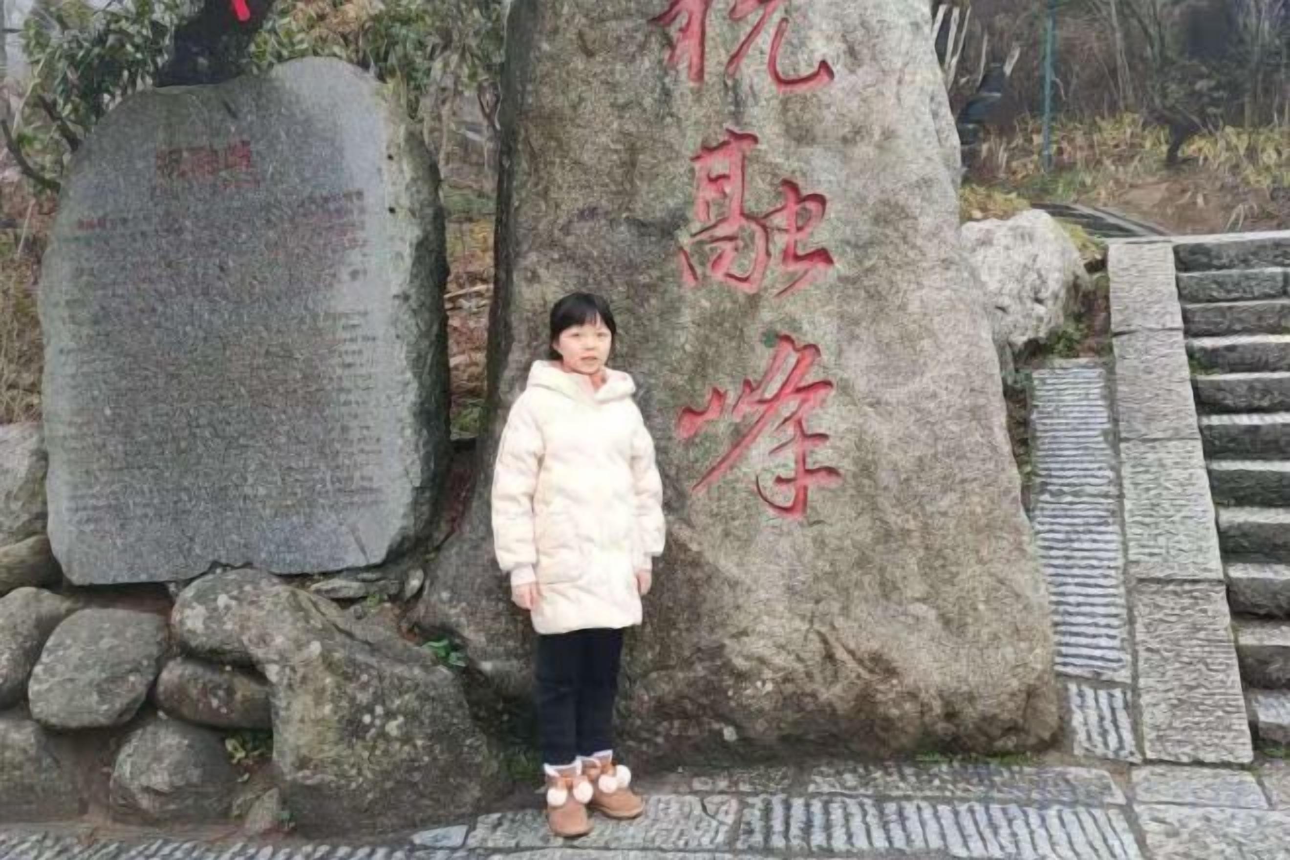 Una persona in piedi di fronte a un imponente monumento in pietra con iscrizioni.