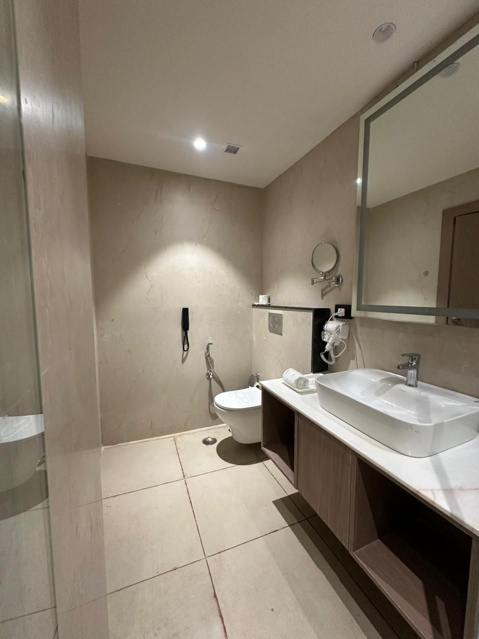 A modern bathroom with a toilet, bidet, and a large sink with a mirror above it.