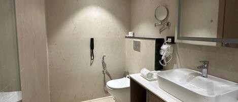A modern bathroom with a toilet, bidet, and a large sink with a mirror above it.
