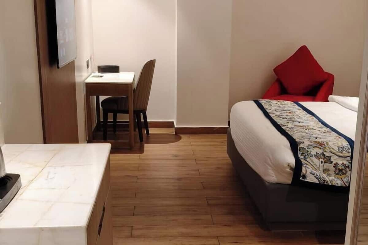Hotellihuone, jossa on sänky, työpöytä, tuoli ja seinälle asennettu televisio.