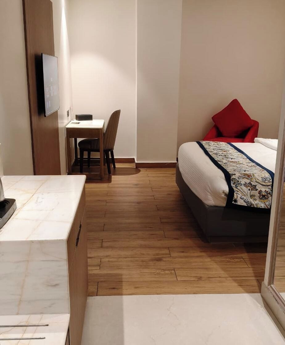 Una habitación de hotel con cama, escritorio, silla y televisor.