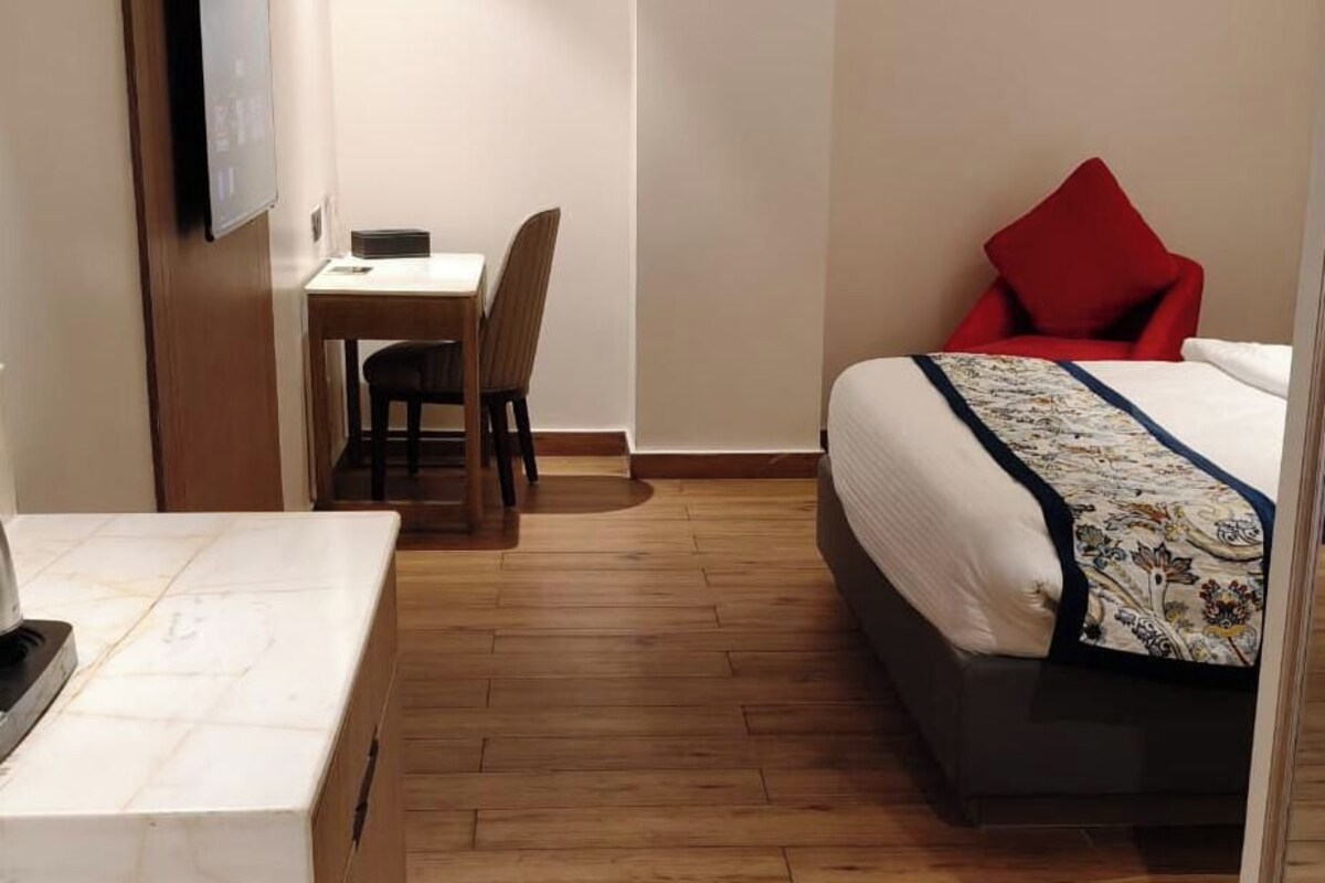 Una camera d'albergo con un letto, una scrivania, una sedia e una TV a parete.
