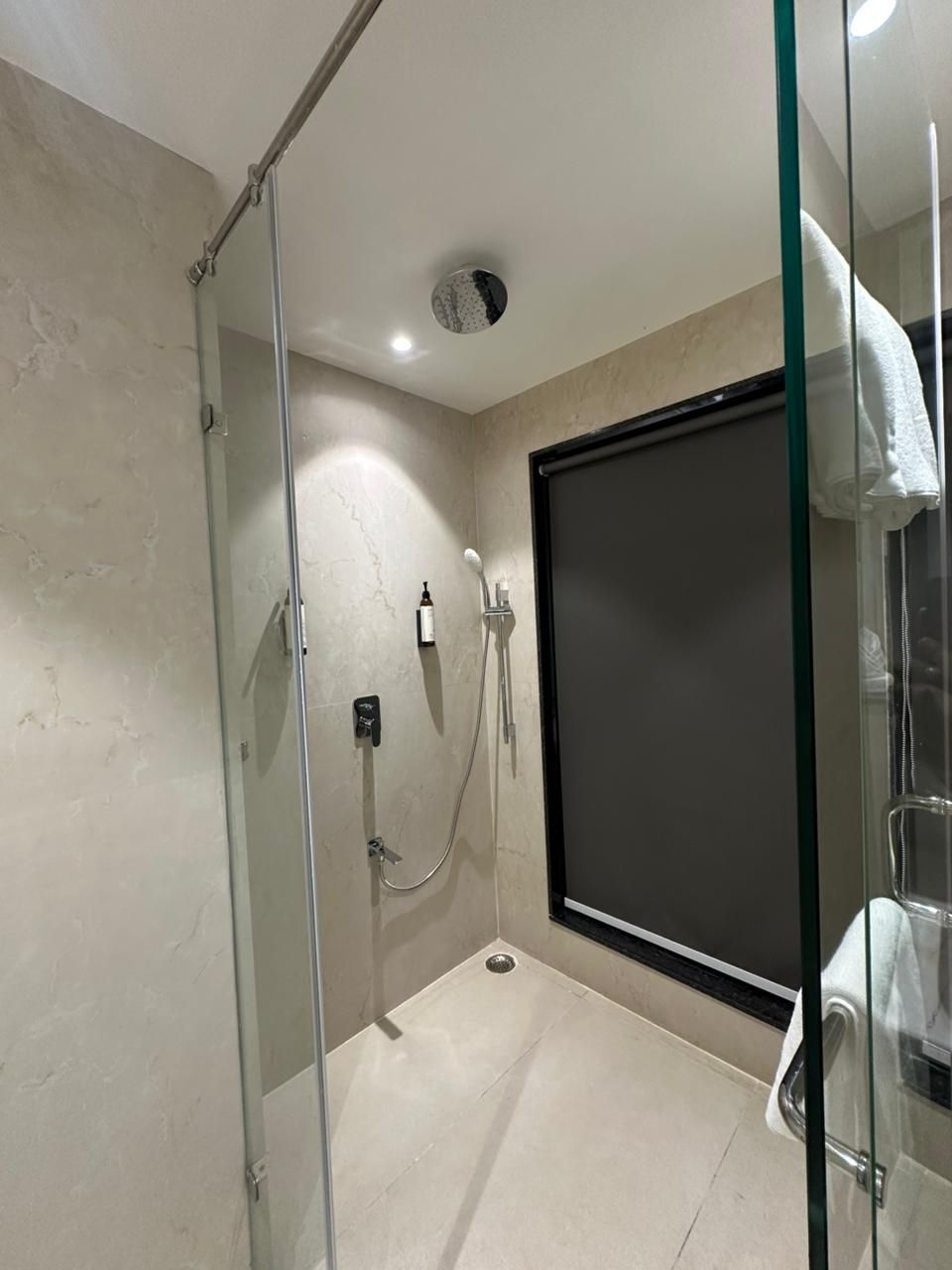 A glass-enclosed shower with a control panel, a dark sliding door, and a towel rack.