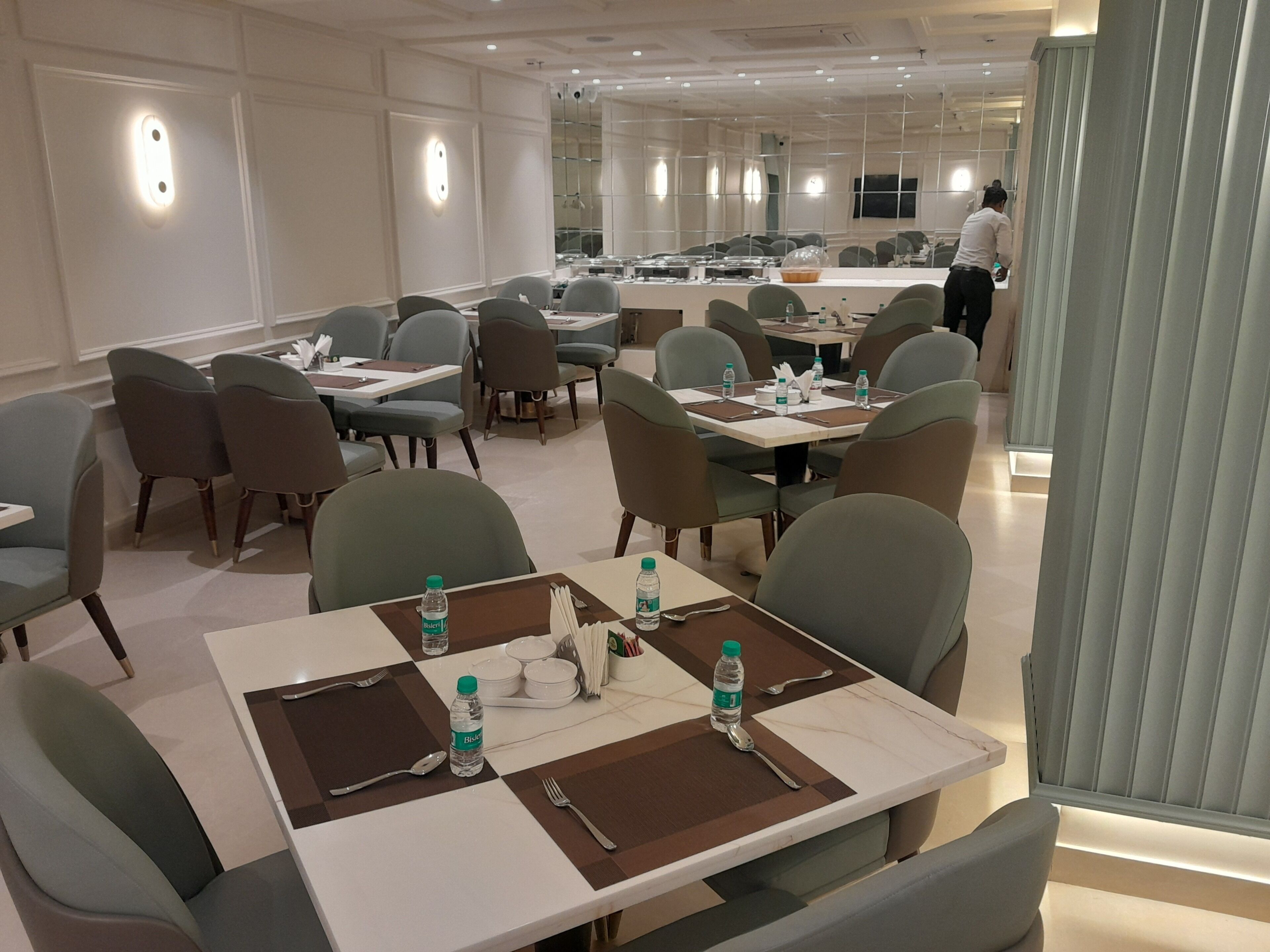 A hotel dining area with multiple tables, chairs, and a person in the background.