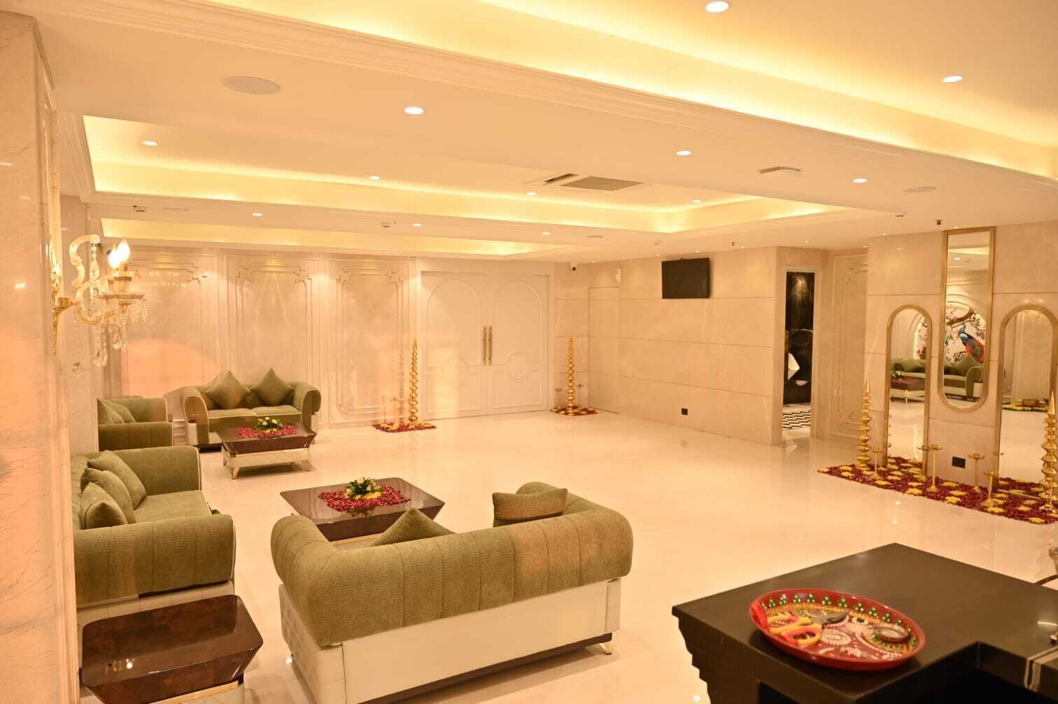 Amplia sala de estar elegantemente decorada, con sofás, una mesa de centro y detalles decorativos como espejos y arreglos florales.