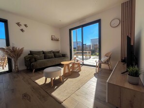 A modern living room with a sofa, ottoman, coffee table, and a TV.