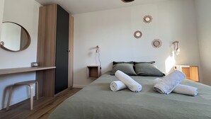 A bedroom with a bed, a bedside table, a mirror, and wall-mounted decor. - La Maison Palulova - Jacuzzi - 400m from the beach (Plouescat)