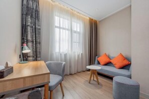 Un salon moderne comprenant un canapé, deux fauteuils, une petite table et une lampe.