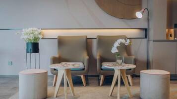 Un área de descanso moderna con dos sillones, una mesita redonda y una lámpara de pie.