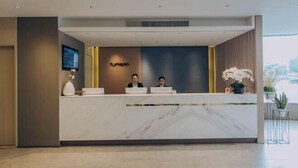 A reception desk with a marble top, two staff members behind it, and a 'Humann' sign on the wall. - Homeinn (Yangzhou)