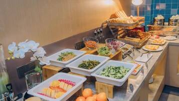Un bufé con diversas opciones de comida, como frutas, ensaladas y otros platos.