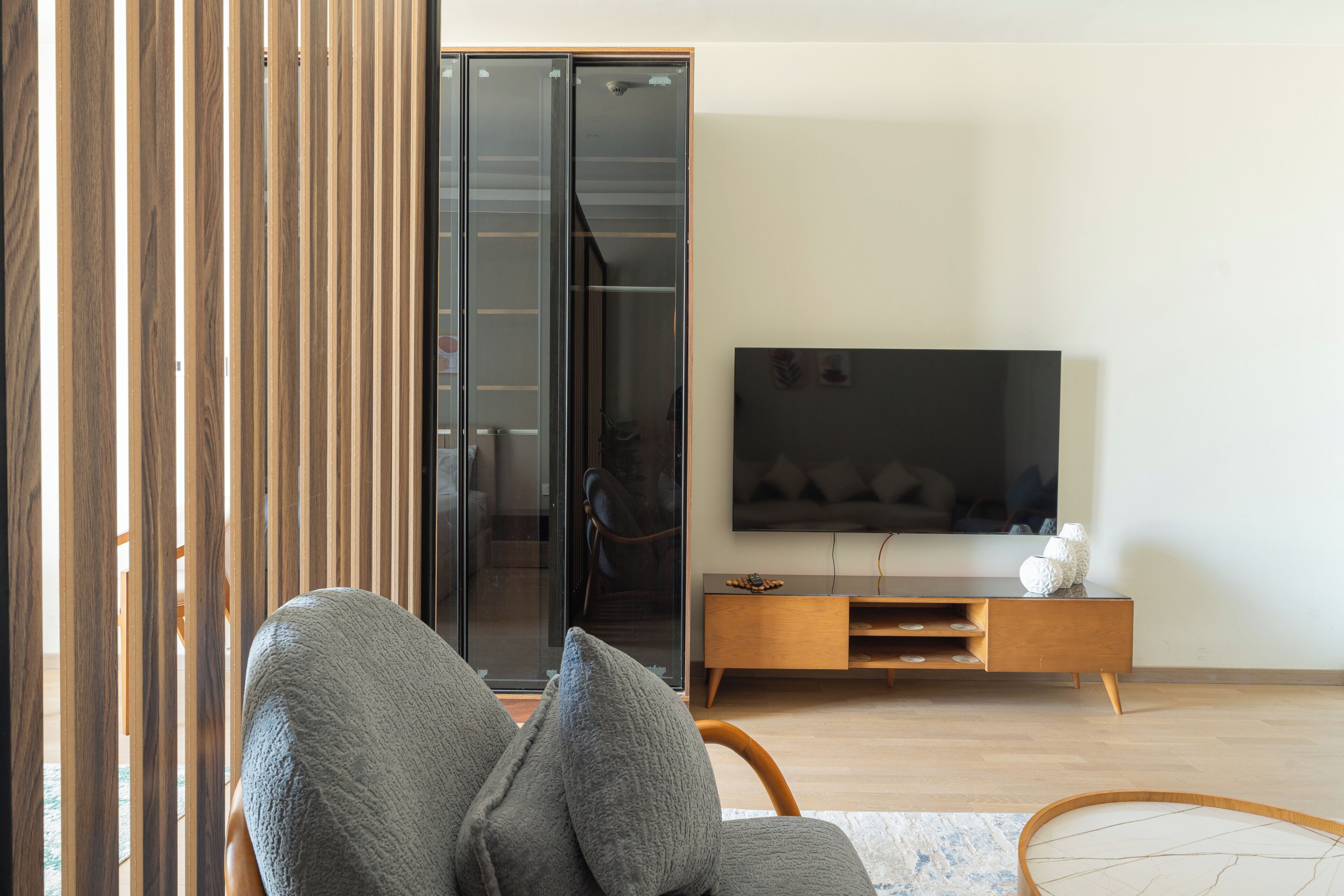 Un salon moderne avec un canapé, un téléviseur, un meuble en bois et une porte-fenêtre coulissante.
