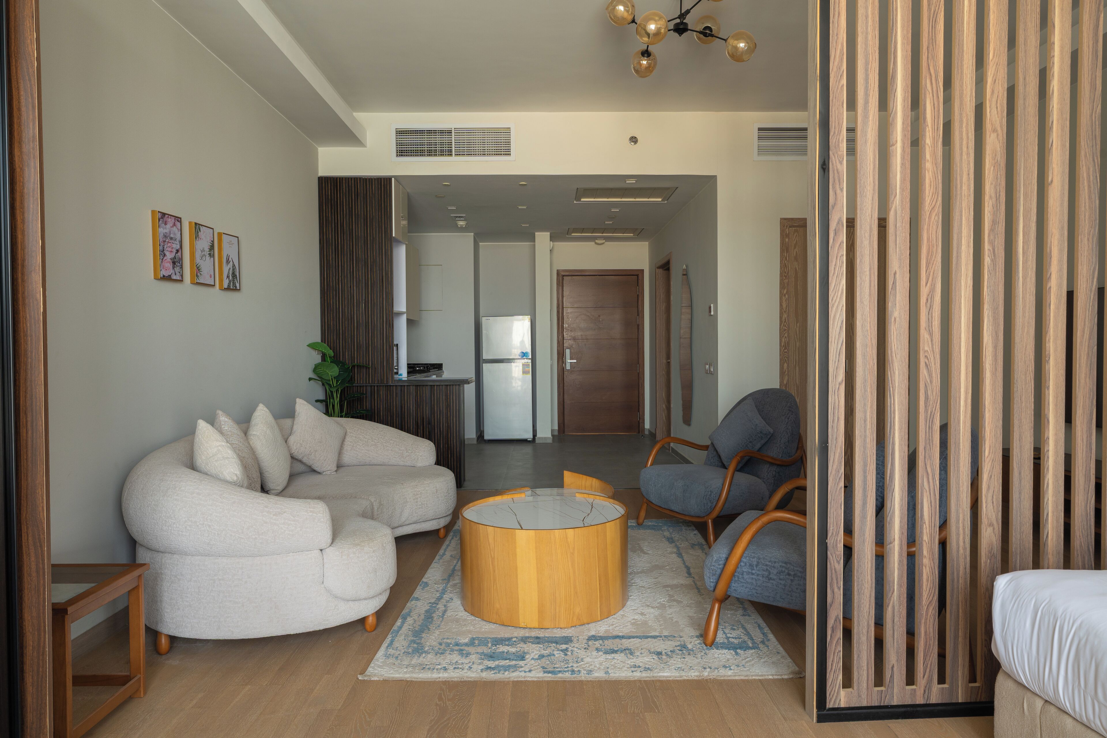 A modern living room with a sectional sofa, a round coffee table, and a wooden partition.