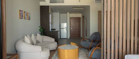 A modern living room with a sectional sofa, a round coffee table, and a wooden partition.