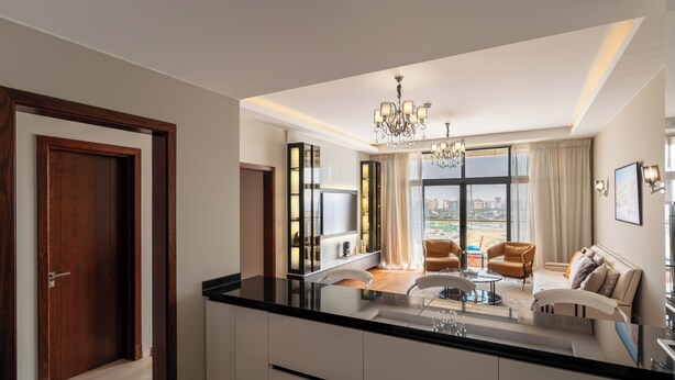 A modern kitchen with a large island, a dining area with chairs, and a view of the city through large windows. - Brassbell l Sheikh Zayed l Aeon Towers  (6th of October City)