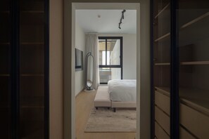 Ein Schlafzimmer mit einem Bett, einer Bank, einem Spiegel und einem Fenster.