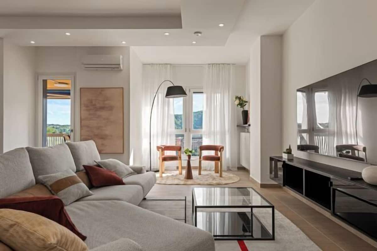 Un salon moderne avec un canapé, une table basse et un téléviseur. Il y a également un coin repas avec des chaises et une table.
