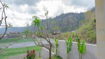 A view of a rural landscape with a concrete wall, a small structure, and a field.