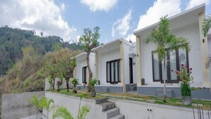 A modern building with multiple rooms, a staircase, and potted plants. - Batur Kencana Villa Mitra RedDoorz (Bali)