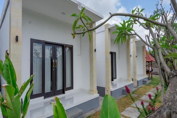 A modern two-story building with a white facade, dark-framed windows, and a small porch area. - Batur Kencana Villa Mitra RedDoorz (Bali)