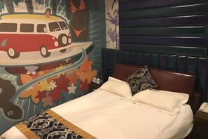 Een bed met hoofdbord, kussen en een muurschildering.