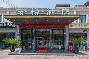 A hotel entrance with a glass facade, a covered entrance area, and potted plants. - Shanghai Baoyue Hotel (Hongqiao Wuzhong Road Branch) (Shanghai)