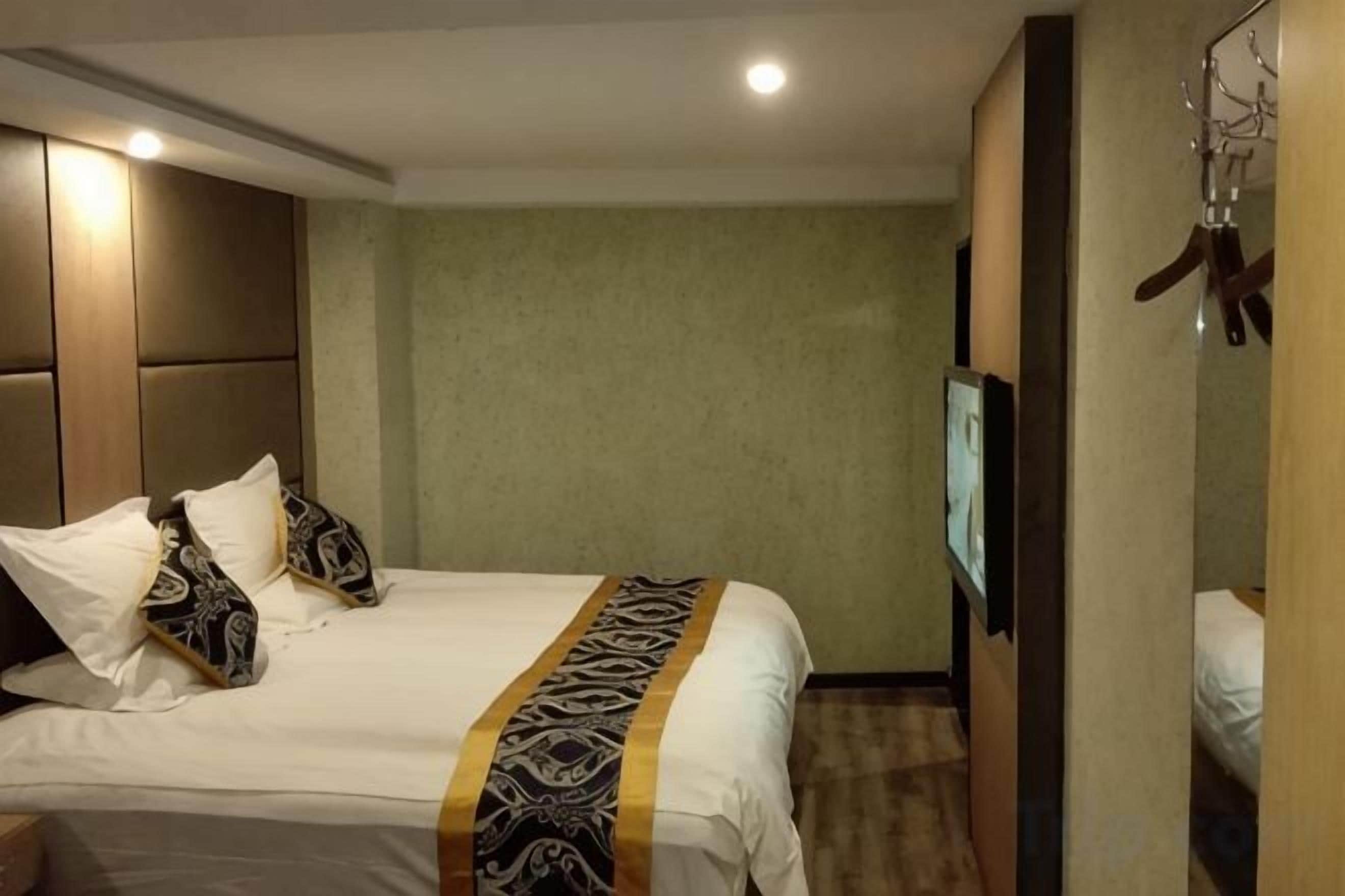 A hotel room with a bed, a television, and a wardrobe.