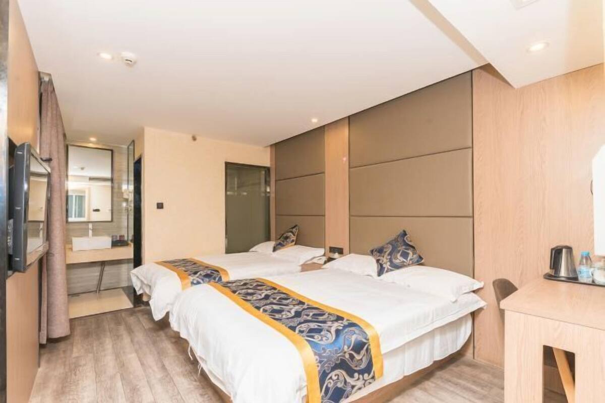 Una habitación de hotel con dos camas, un escritorio de madera, un espejo y un televisor.