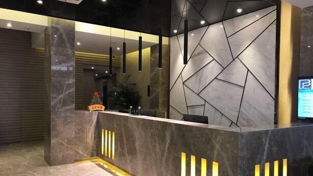 Una moderna zona de recepción con mostrador de mármol, tiras de luz verticales y un diseño de pared geométrico.