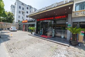 A hotel entrance with a red awning, a visible phone number, and a potted plant outside. - Shanghai Baoyue Hotel (Hongqiao Wuzhong Road Branch) (Shanghai)