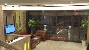 A lobby with a reception desk, leather seating, a large plant, and a staircase.