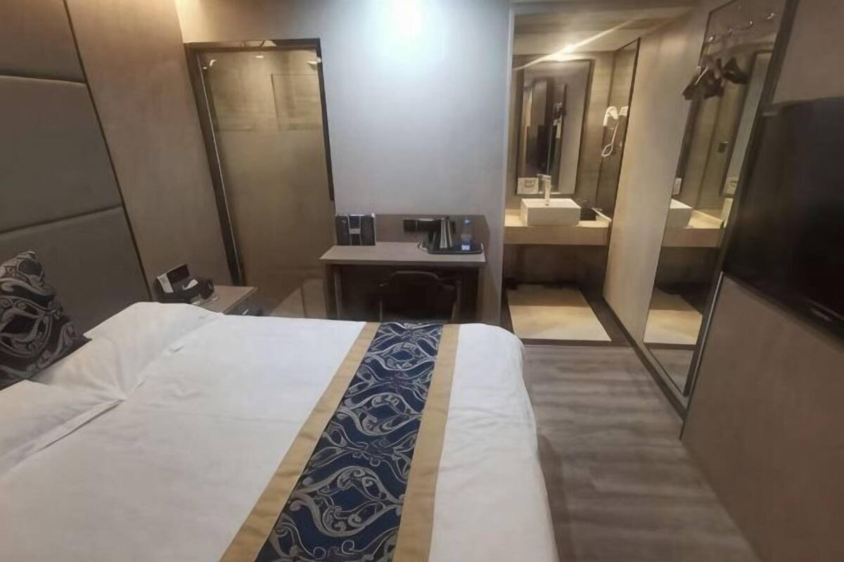 Una habitación de hotel con cama, escritorio, silla, espejo y televisor.