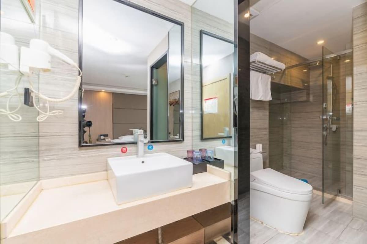 Een moderne badkamer met een grote spiegel, een witte wastafel, een toilet en een douchecabine.