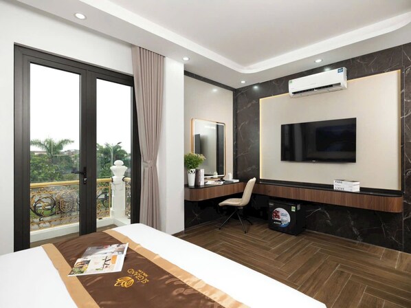 Una habitación de hotel moderna con una cama grande, un escritorio con silla, un televisor y un equipo de aire acondicionado.